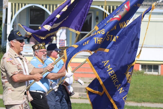 Veterans carry American flags while marching in a Northern Michigan parade.